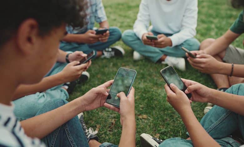 adolescents assis en cercle regardant un smartphone